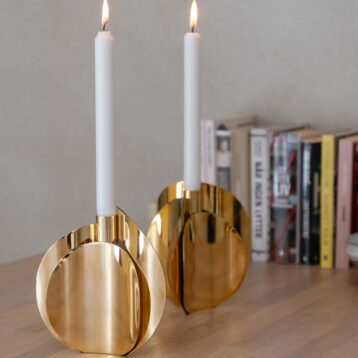 Lysestake i messing plassert på en kjøkkenøy. Beige bakgrunn inkludert bøker.