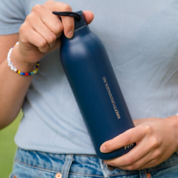 Bilde av person som holder termoflaskei marineblå