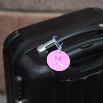 Bilde av rosa bagasjetag plassert på svart koffert.