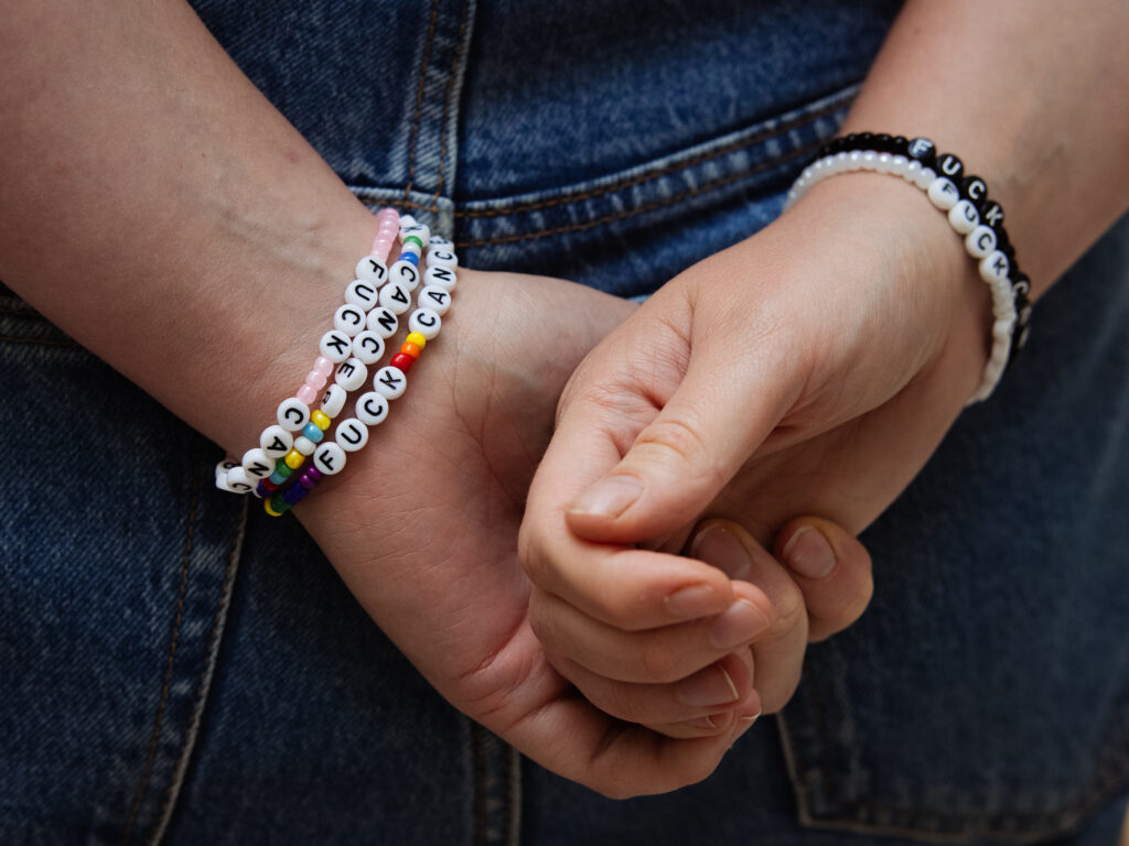 Bilde av foldede hender med armbånd. Blå bakgrunn